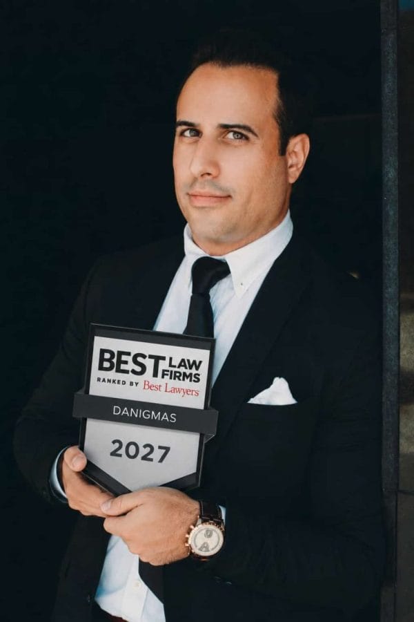danigmas - IP | C. Abogados News Professional man in a suit holding a 'Best Law Firms' award plaque that reads 'DANIGMAS' and the year '2027'.